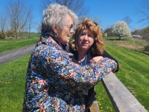 Life Engagement Manager Maria G. and a resident pause on a sunny spring day to take in the landscaped grounds and flowering trees beside the 1 mile walking path.